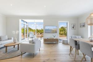 a living room with white furniture and a table at De Bööi - Luxus-Haus mit Meerblick, Sauna & Kamin in Fehmarn