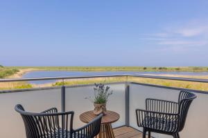 a balcony with two chairs and a table with a vase on it at De Bööi - Luxus-Haus mit Meerblick, Sauna & Kamin in Fehmarn
