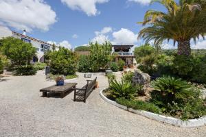 un giardino con panchina e palme e un edificio di Quinta das Achadas - Quartos a Cerro Ruivo