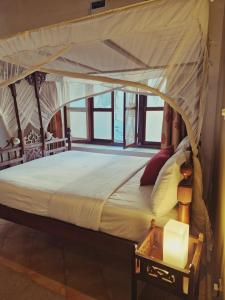 een slaapkamer met een hemelbed en een tafel bij Stone Town Cafe in Zanzibar City +13 foto's
