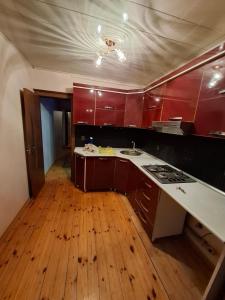 a kitchen with red cabinets and a wooden floor at Deniz Hotel in Ganja