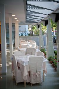 a row of white tables and chairs in a restaurant at Hotel Derby in Riccione