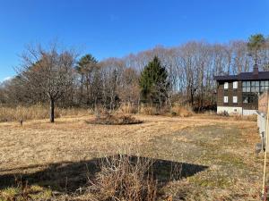 un campo vuoto davanti a una casa di ペンション歩野慕野-honobono a Kitashiobara