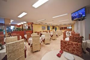 a restaurant with tables and chairs and a flat screen tv at Hotel Derby in Riccione
