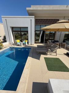 a swimming pool with chairs and an umbrella at Villa Laguna Lux TU10 in Salalah +28 photos