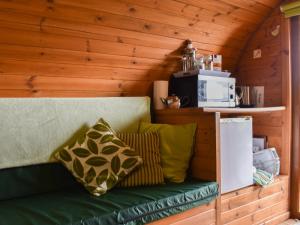 eine grüne Couch mit Kissen in einem Zimmer in der Unterkunft Rivendell Glamping Pod - Uk11881 in North Tamerton
