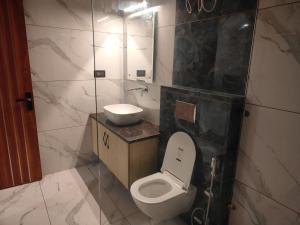 a bathroom with a white toilet and a sink at Golden Heights in Dehradun