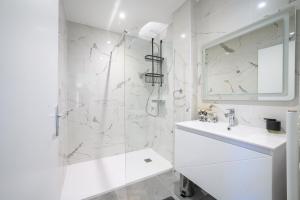 a white bathroom with a shower and a sink at Le boudoir du Palais in Périgueux