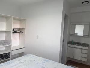 una stanza bianca con un letto e una cucina di Apartamento proximo centro a Poços de Caldas