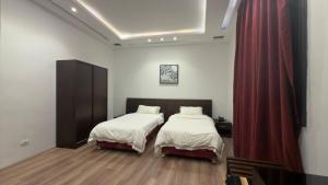 的黎波里فندق الجرات的一间卧室设有两张床和红色窗帘 更多6张照片