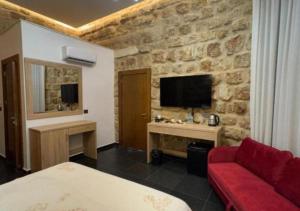 Una habitación de hotel con un sofá rojo y un televisor. en Villa Rosa Luxury Boutique Hotel, en Batroun