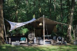 a tent with a table and chairs in a forest at Forest Inn in Ugchelen