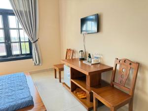 a room with a desk and a table and chair at Khách Sạn Đối Ngoại Biên Phòng in Buon Ma Thuot