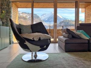a chair in a living room with a large window at Apartment Mountain 4U by Interhome in Meiringen