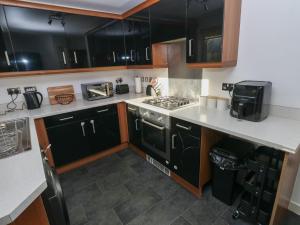 a kitchen with black cabinets and a stove at Swansea Escape in Swansea