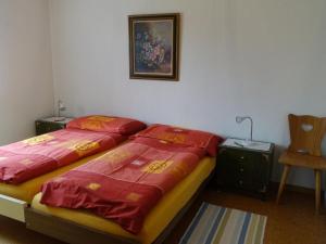 a bedroom with two beds with red sheets and a chair at Apartment Akalei by Interhome in Aeschi
