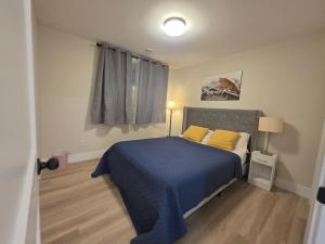 een slaapkamer met een blauw bed met gele kussens bij Quiet Comfort Suite in Moncton
