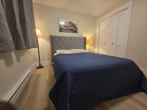 een slaapkamer met een bed met een blauwe deken bij Quiet Comfort Suite in Moncton