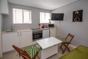 een keuken met witte kasten en een tafel en stoelen bij SeaPoint MicroStudio - Walk 2 Promenade&Waterfront in Kaapstad +16 foto's