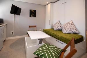 een kleine kamer met een bureau, een bed en een tafel bij SeaPoint MicroStudio - Walk 2 Promenade&Waterfront in Kaapstad