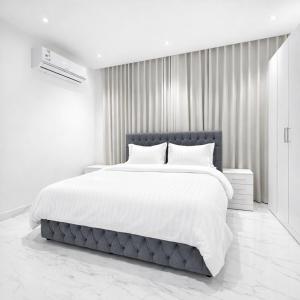 una camera da letto bianca con un grande letto con lenzuola bianche di Najd Cozy Apartment a Dammam Altre 21 foto