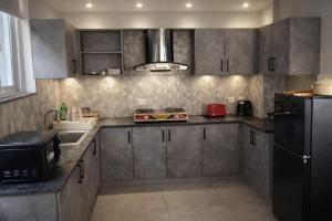 a kitchen with gray cabinets and a black refrigerator at Haven Mushkpuri Terraces Khaira Gali - 3BR Home, Lawn, BBQ & Fireplace in Chhāngla Gali +20 photos