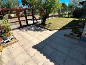 een patio met een houten hek en een boom bij Casa aconchegante perto do mar em Imbé in Imbé