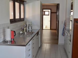 a kitchen with white cabinets and a sink and a hallway at Apartment Wohnung Bellevue by Interhome in Chevenez