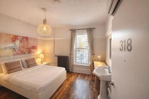 een slaapkamer met een bed, een wastafel en een raam bij Auberge du Plateau in Montreal