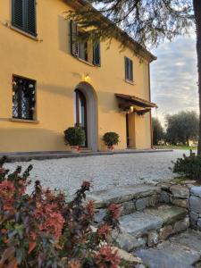 een groot geel huis met een stenen oprit bij Il Casale Naturart in Lucciano