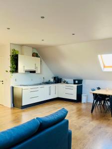 a living room with a blue couch and a kitchen at Ruime studio met eigen ingang en private badkamer in Opwijk