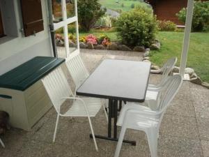 a white table and two white chairs on a patio at Apartment Chalet Bärli by Interhome in Fiesch