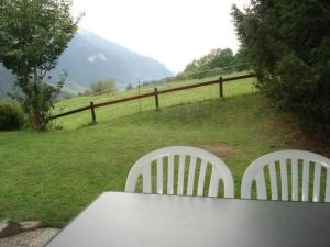 two white chairs sitting at a table in a field at Apartment Chalet Bärli by Interhome in Fiesch +2 photos