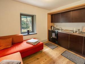 a living room with a red couch and a kitchen at Holiday Home Eggwald by Interhome in Wassen