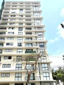 a tall white building with a tree in front of it at Brand New Apartment in Lima