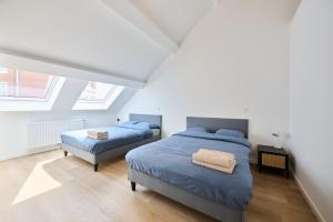 two beds in a bedroom with white walls and wood floors at Toison d'Or House 4 in Brussels
