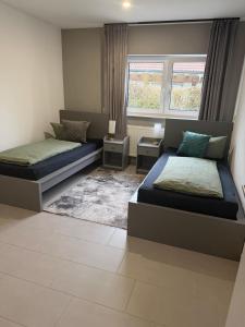 una camera da letto con due letti e due finestre di Tiger Apartment a Sinsheim