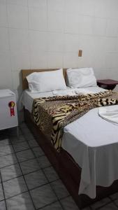 een slaapkamer met twee bedden met witte lakens en een luipaarddeken bij Pousada Mamulengo in Porto De Galinhas