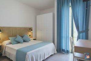 een slaapkamer met een bed met blauwe gordijnen en een bureau bij Zeeva Hotel and Resort in Torre Dei Corsari