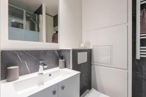 une salle de bains blanche avec un lavabo et un miroir dans l'établissement La Résidence Le Belvédère - Avec Balcon, à Le Tholy 7 autres photos