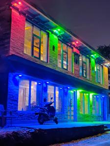 a motorcycle parked in front of a building with colorful lights at Nandi Roop Homestay in Panuānaula