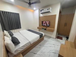 a bedroom with a bed and a tv on a wall at Hotel meghshyam in Sānand +11 photos