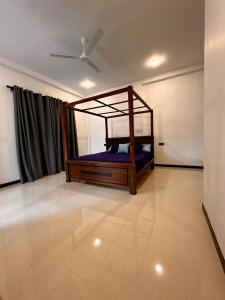 a bedroom with a bed with blue sheets and a fan at The Regent Villa in Unawatuna
