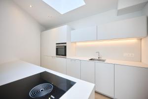 a white kitchen with white cabinets and a sink at Toison d'Or & saunna 2 in Brussels