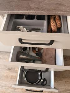 a drawer in a cabinet filled with dishes at Ūla Apartments in Mažeikiai +5 photos