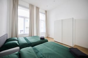 a bedroom with two green beds and a large window at Toison d'Or & saunna 2 in Brussels