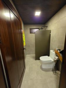 een badkamer met een toilet en een kraam met een deur bij San Vicente Mountain in Colón
