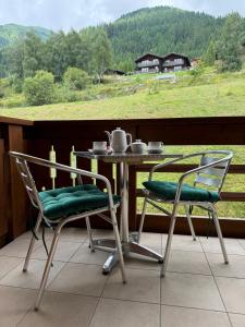 2 stoelen en een tafel op een balkon met uitzicht bij Cozy Studio with Wellness in Goms in Blitzingen