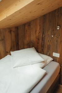 a bed with white sheets and a wooden wall at Hotel Matterhornblick in Zermatt +118 photos