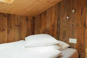 a bedroom with wooden walls and a bed with white pillows at Hotel Matterhornblick in Zermatt